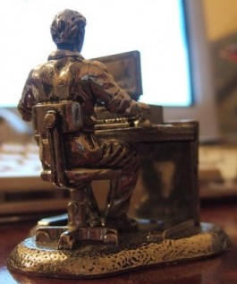 Beeldje van een man aan een bureau met een computer