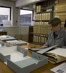 Vrouw verpakt papieren erfgoed in zuurvrije dozen