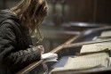 Vrouw maakt aantekeningen bij oud boek in vitrine in Museum Plantin-Moretus