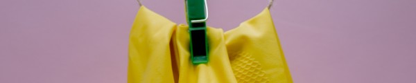 Twee gele schoonmaakhandschoenen aan een waslijn opgehangen