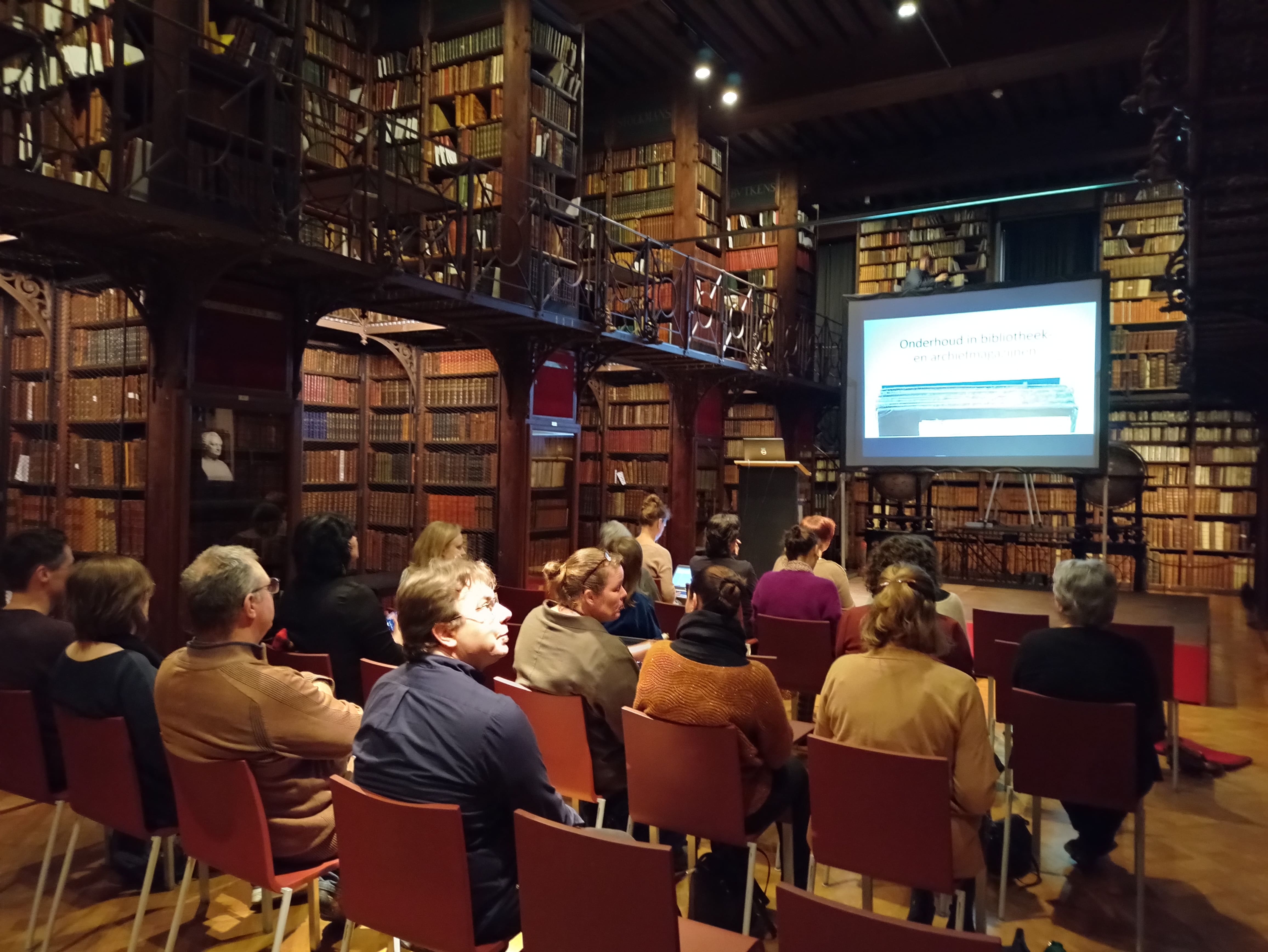 Mensen volgen een presentatie in de setting van een bibliotheek